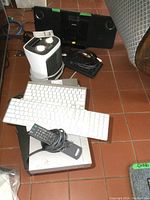 Photo showing the portable heater, multiple keyboards in black and white, and remote control on top of VHS player and DVD player.