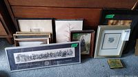 Grouped view of multiple framed prints of varying sizes leaning against wood paneling, showing size range and frame styles.