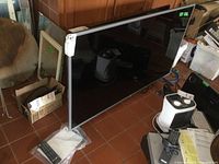 Front side angled view of the LG 47-inch LED TV with visible remote and manual on the base stand.