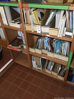 Full view of 5 cubbies containing assorted vintage magazines and postcards, arranged in cardboard holders and shelves.
