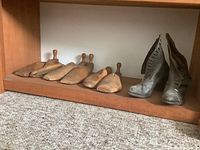 Shelf with five wooden shoe stretchers lined up, showing different sizes and traditional wooden handles.