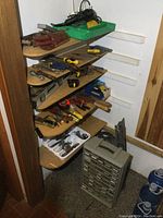 Photo showing wooden shelves filled with various hand tools including pliers, screwdrivers, clamps, and a cordless Milwaukee drill with charger.