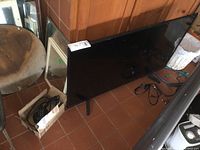Image showing Toshiba 43 inch TV set on stand with remote and cables nearby on floor.