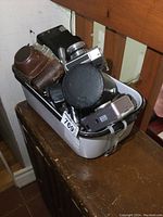 Bin containing multiple vintage cameras including Kodak Brownie Hawkeye and rangefinder style cameras