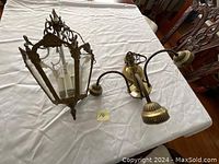 Two antique ceiling lamps laid out on table showing different styles and condition.