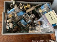 Top view of a bin filled with assorted antique door knobs and hardware, including various materials and styles.
