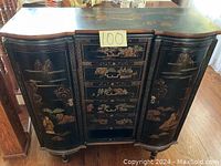 Front view of Asian cabinet showing curved top, painted side doors with figures and landscape, and central drawers also painted.
