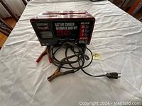 Red Century D700 battery charger with cables and power cord on white cloth background.
