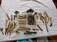 Top-down photo of assorted brass and metal window and door locks laid out on white cloth.
