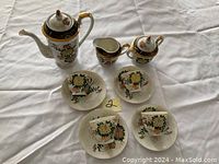 Full view of four cups and saucers with pot, creamer and sugar bowl showing floral pattern and gold accents