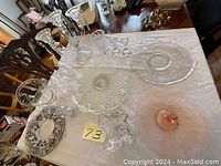 Photo of the lot showing various crystal plates, glass dishes, and candle holders arranged on a table.