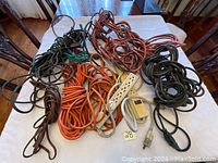 Photo of various used extension cords and a power strip laid out on a surface.
