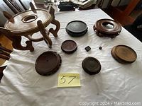 Eight wooden Asian-style display stands of different sizes arranged on a white cloth, showing various shapes and carved details.