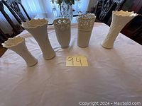 Image of all five white Lenox vases placed in a row on a table, showing different shapes and decorative designs