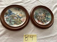 Two round wooden frames with porcelain plaques showing birds and nests.