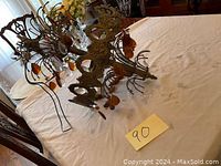 Photo showing vintage metal chandelier with amber-colored and clear crystal drops lying on a table, with intricate metal arms and decorative design.