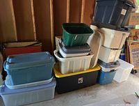 Overall view of stacked plastic storage bins in multiple colors and sizes showing condition and assortment.