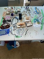 Overview of all items including necklaces, brooches, sunglasses, bracelets laid out on table.