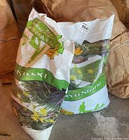 Two 28 kg bags of Deco Stone play and work sand, one opened and one sealed, placed on a garage floor.