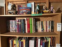 Bookshelf showing a dense collection of Dick Francis novels and other books, with several colorful figurines on top shelf including nativity scenes.