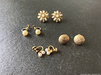 Four pairs of gold filled earrings displayed against a dark surface showing styles and condition.