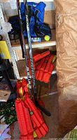 Two Bauer hockey sticks next to four orange life jackets on shelf