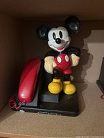 Mickey Mouse vintage landline phone showing figure, red handset, and black base inside cardboard box.