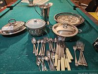 Full view of all items on green felt surface showing cutlery, serving dishes, trays and pitcher