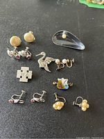 Top down view of lot showing five pairs of screw back sterling silver earrings and four pins brooches on flat surface