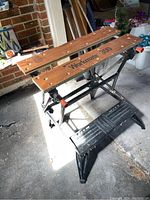 Front-angle view of Black and Decker Workmate 300 workbench showing wooden top with logos and black frame