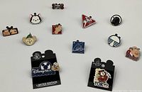 Overview photo of the Disney pin lot showing multiple colorful enamel pins arranged on a white surface including character heads and themed icons