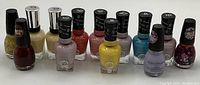 Photo shows 13 new nail polish bottles from brands Miracle Gel, Sinful Colors, and others in various colors including beige, red, yellow, blue, purple, and glitter finishes.