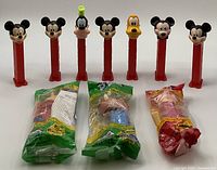 Seven vintage PEZ dispensers featuring Mickey Mouse (five), Goofy, and Pluto heads, along with three sealed PEZ dispensers from Disney characters Piglet, Winnie The Pooh, and Pumbaa in bags.