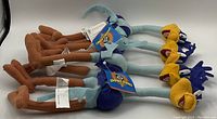 Multiple identical Looney Tunes Roadrunner plush toys laid out in a row, showing color and condition