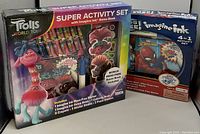 Photo showing Trolls World Tour Super Activity Set boxed with colorful packaging and multiple activity components, alongside Spider-Man 4-in-1 Activity Set in smaller package.