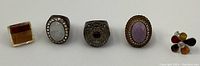Five large vintage rings arranged side by side showing various earth tone stones and metal settings.