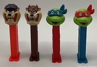 Four vintage Pez dispensers: two Tasmanian Devil characters and two Ninja Turtles characters on colored bases. Clear detailed facial features typical of Pez dispensers.