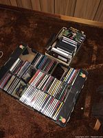 Two open boxes filled with numerous CDs and DVDs with visible titles and artists.