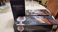 Photo of Bohemia Crystal Orion vase box alongside two Cristal D'Arques Longchamp stemware boxes on a table.