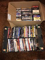 Photo showing two boxes tightly filled with DVDs and VHS movies, with spines and covers visible representing various titles and genres.