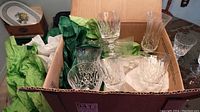 Open box showing various glasses including several wine glasses and parfait glasses nestled in tissue paper.