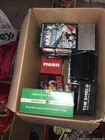 Top view of box with various DVD sets including Monk, Smallville, The Shield, Sons of Anarchy, Malcolm in the Middle.