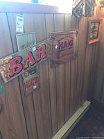 Photo showing 4 vintage mirrored bar signs on wood panel wall, including two 'BAR' signs in red and yellow, a Haig whiskey advertisement, and a small 'WANTED' sign