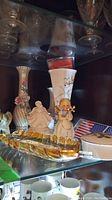 Shelf displaying glass leaf dish, figurines, trinket box, and vases