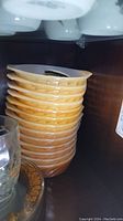Stack of eleven vintage Fire King individual size baking dishes with yellow-orange swirl exterior.