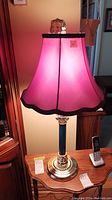 Vintage lamp with pink fabric lampshade and ceramic-metal base on wooden table
