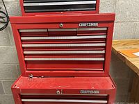 Front view of large red Craftsman tool box with drawers closed, showing locks and brand logo.