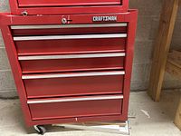 Front view of red Craftsman tool box showing logo, lockable top compartment, and 5 drawers with metal handles.