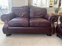 Front view of burgundy leather loveseat showing rolled arms and seat cushions
