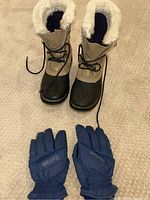 Top view of Sorel boots and blue gloves on carpet